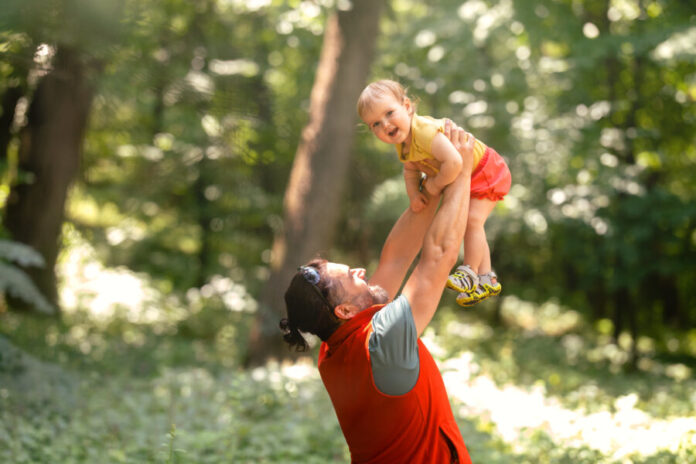 man-lifting-toddler-in-a-forested-area-2026-03-17-00-16-30-utc